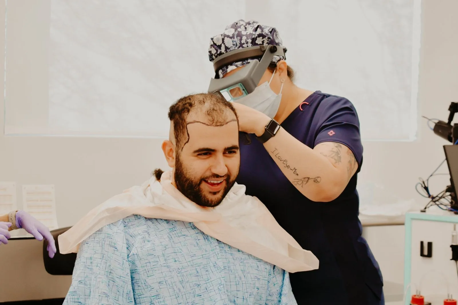 Clinician in protective gear measuring a patient's head with a specialized device during a consultation